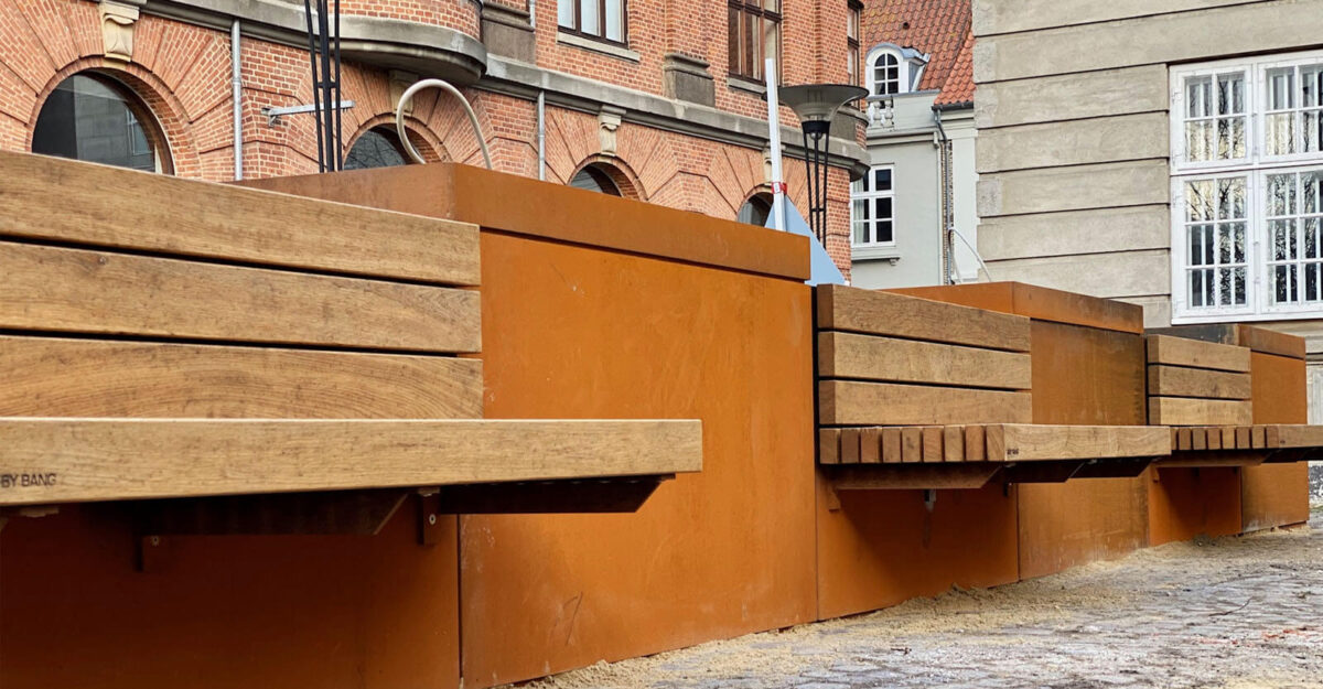 områdefornyelse af Mathilde Fibgers Have i Aarhus med By Bangs plantekummer i cortenstål med bænke monteret på sider, som er beklædt med mahogni planker