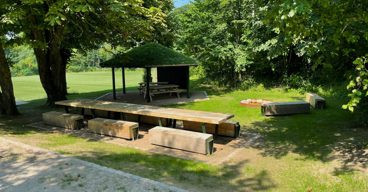 et bordbænkesæt i solidt egetræ og med metalelementer malet i grøn står i parken