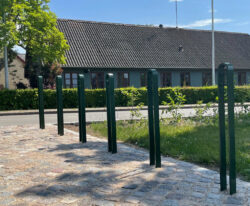 en række cykelparkerings steler fremstillet i malet galvaniseret stål står i parken i Nørre Søby
