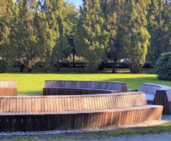 en stor modulopbygget cirkelbænk i galvaniseret stål og beklædt med mahogni stave i parken ved Tønder Gymnasium