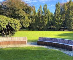en stor modulopbygget cirkelbænk i galvaniseret stål og beklædt med mahogni stave i parken ved Tønder Gymnasium