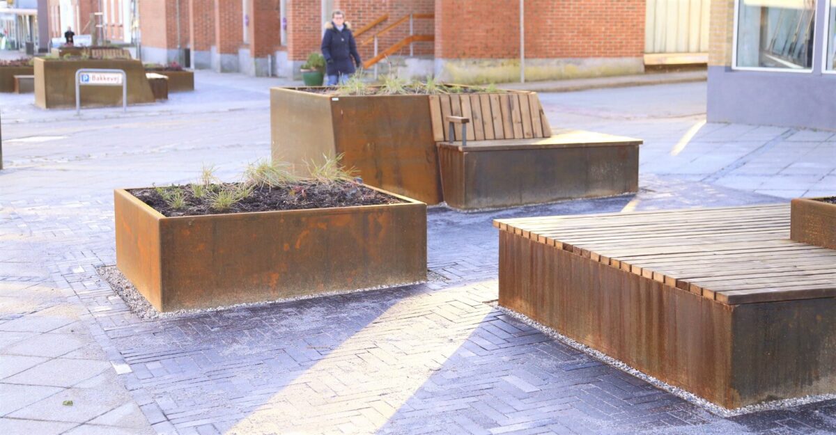 Plantekasser i cortenstål med indbyggede bænke og plads til planter, Langå by midt