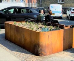 en unik plantekasse i cortenstål med en bænk af mahogni planker på Frederiksbergs gade