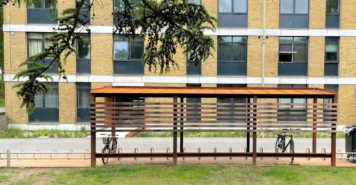 Casa 44 modulopbygget cykeloverdækning i cortenstål med installeret cykelstativer og beklædning af mahogni planker