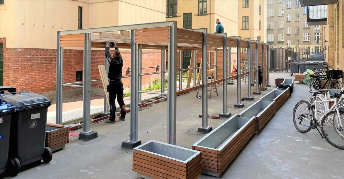 fremstilling af pergola-lignende overdækninger beklædt med træ til at indeholde affaldsbeholdere i Puggaardsgades karréen i København