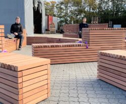 en række bænke specielt designet til dette projekt, lavet af galvaniseret stål og beklædt med mahogniplanker står i gården af By Bangs værksted til Puggaardsgade