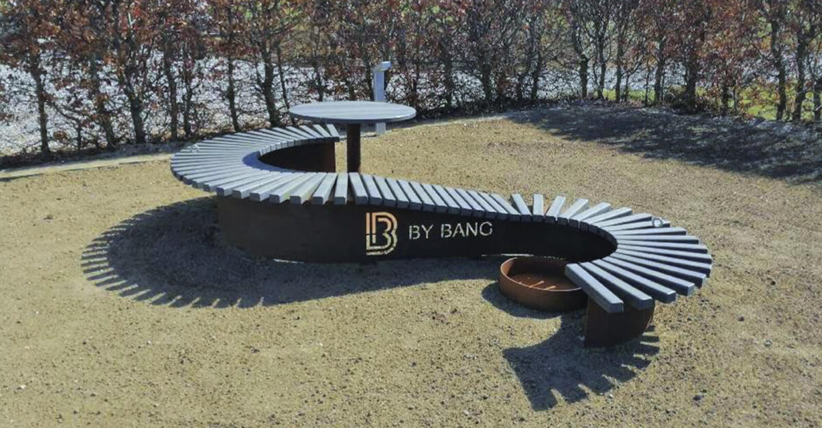 Snoet plint fremstillet omkring et cafebord og en plantering; plinten er beklædt med genbrugsplast planker og fremstillet i corten stål