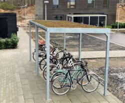 Casa 01 cykeloverdækning i galvaniseret stål med en række af cykelstativer til mange cykler og et sedum tag
