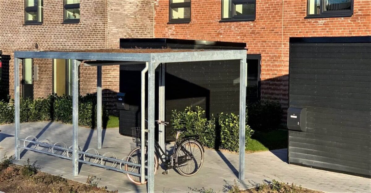 casa 01 cykeloverdækning i galvaniseret stål med en række af cykelstativer til mange cykler og et sedum tag