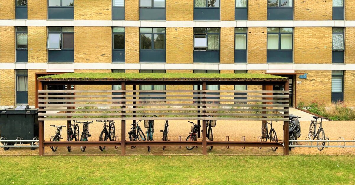 en modulopbygget cykeloverdækning i cortenstål med installeret cykelstativer og beklædning af mahogni planker