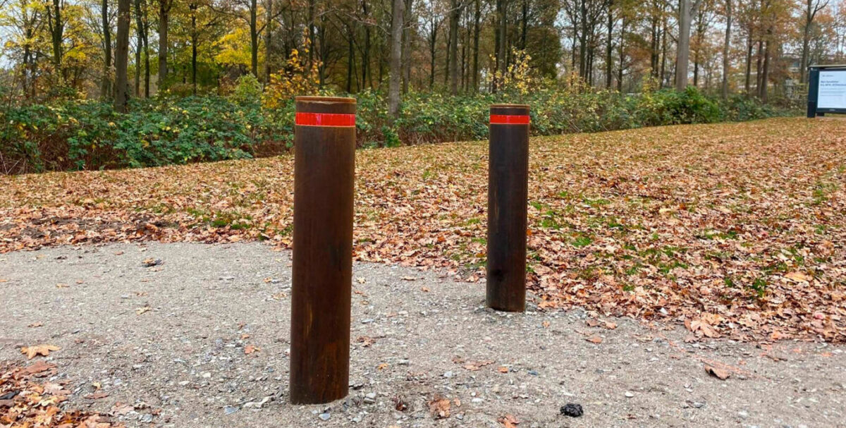 to cortenstål pullerter med røde reflekser på sti