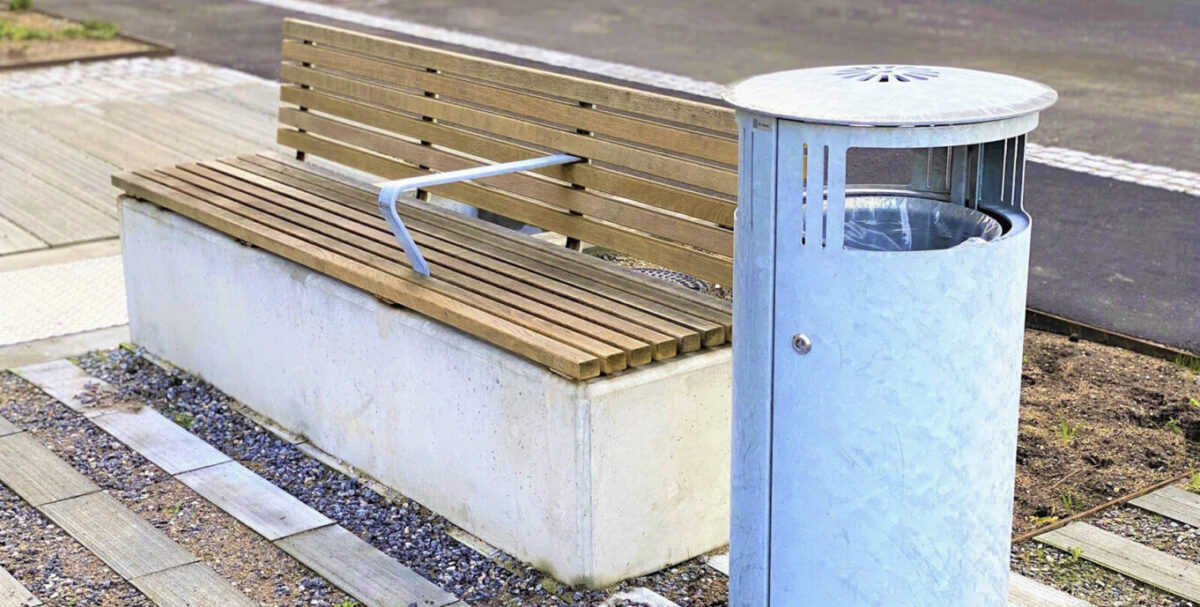 bænk på beton som plint ved siden af an galvaniseret skraldespand