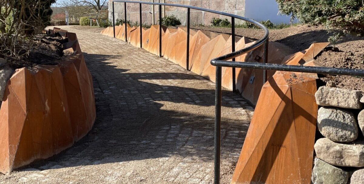 corten stensætning i 5 mm cortenstål med 452 trekantede plader og belysning danne en ny stensætning ved Elev Kirke, et moderne design fra By Bang