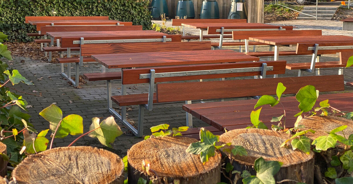 en række store bordbænkesæt i galvaniseret stål og beklædt med lakeret mahogni planker